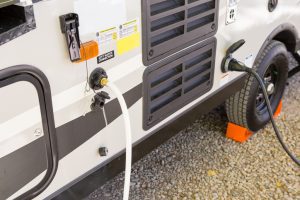 RV water and power hookups with hose and power cable attached.